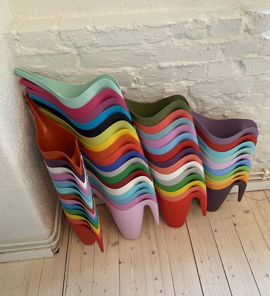 A multicolored stack of Vållö watering cans against the wall in the designer's studio