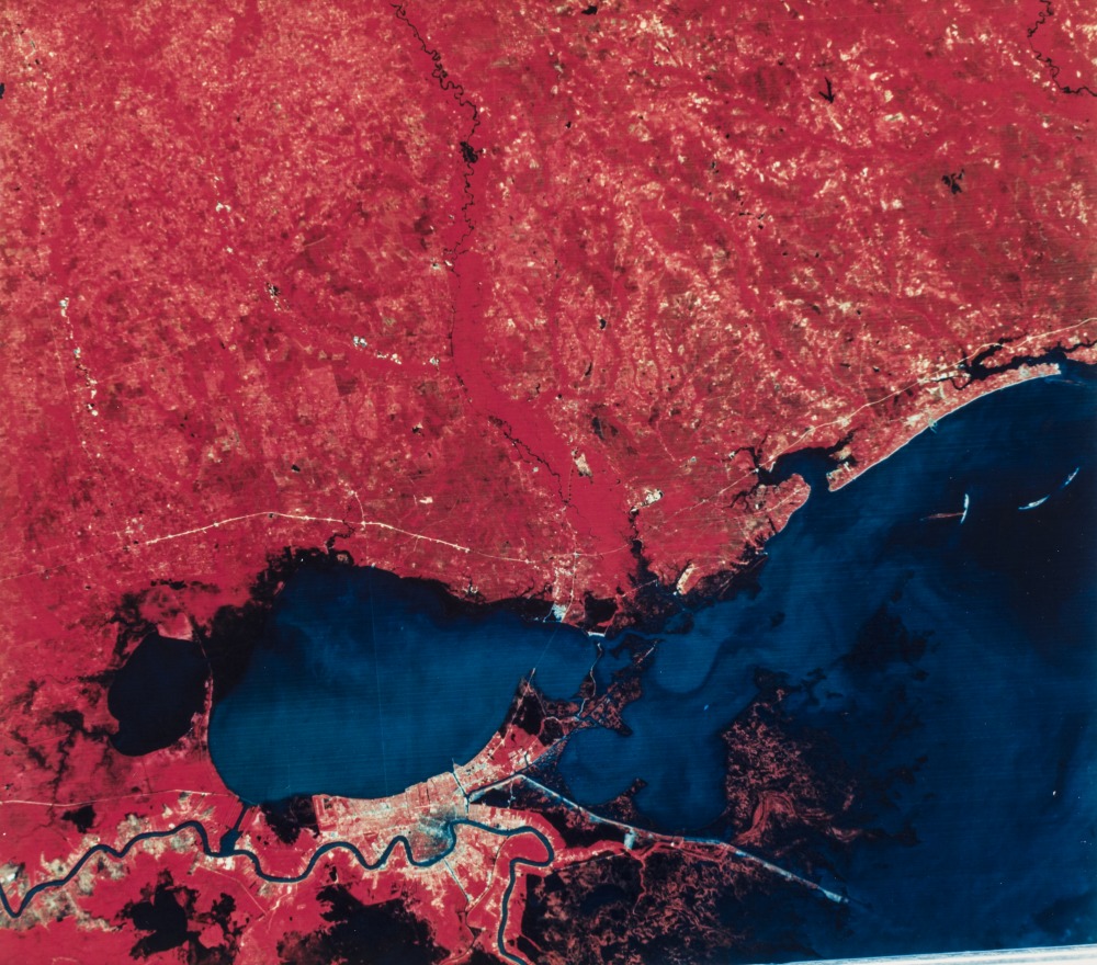 An aerial photograph shows New Orleans and the Northshore following the opening of the Bonnet Carré Spillway. Land is represented in red and water is represented in blue.
